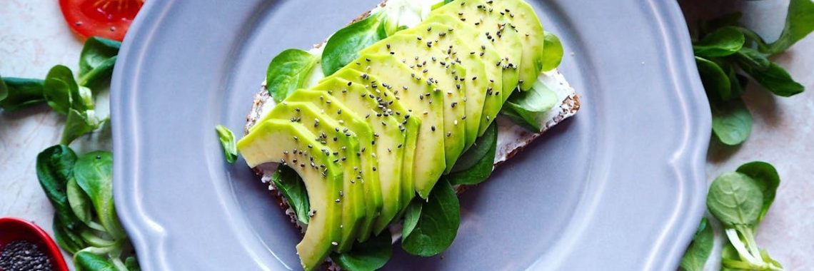 Delicious avocado toast with chia seeds and fresh tomatoes on a grey plate.