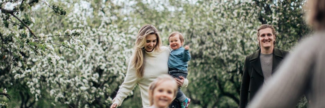 A joyful family enjoys a playful day outdoors amidst blossoming trees in spring.